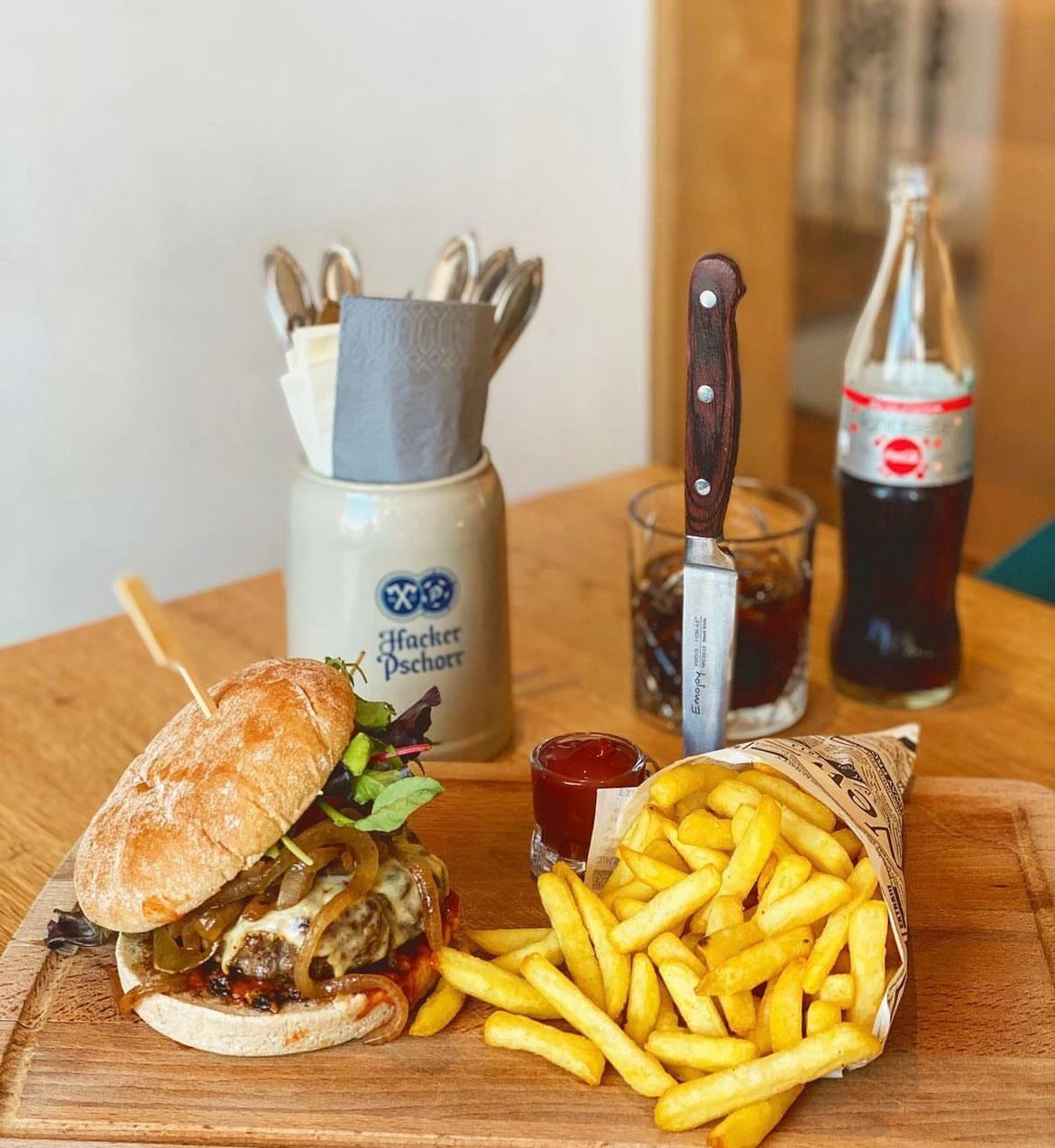 Burger mit Pommes und Cola auf dem Holzbrett im Wirtshaus